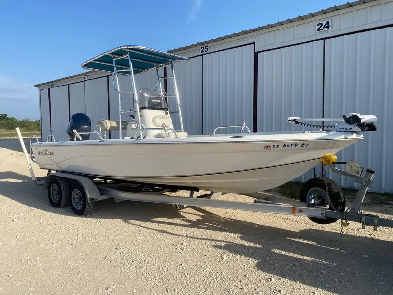 Slide: The Image of 2015 NauticStar 2200 Sport boat on trailer, parked near storage units. - 1