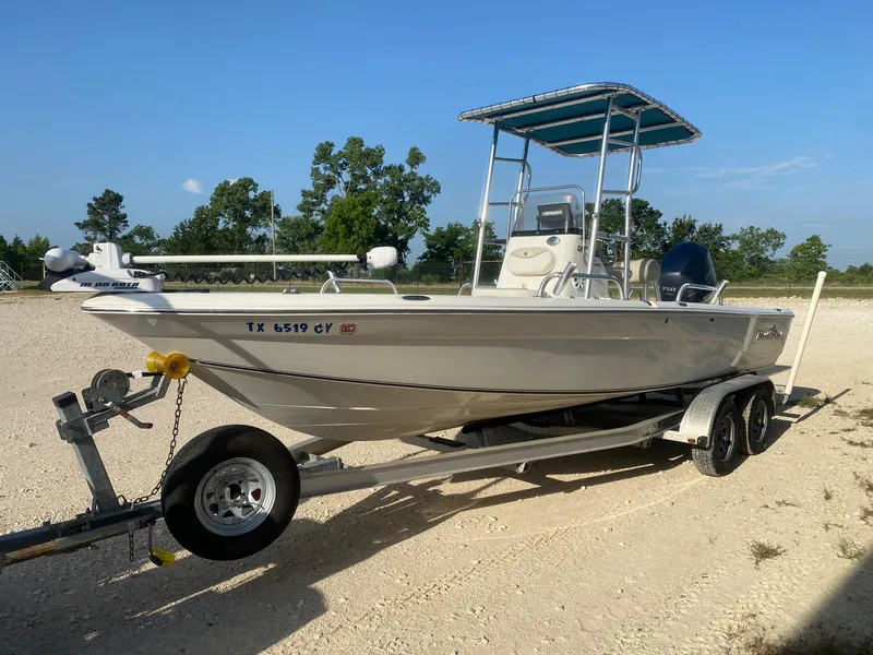 Slide: The Image of 2015 NauticStar 2200 Sport boat on trailer, parked outdoors under clear blue sky. - 2