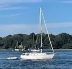 Slide: The Image of 1978 Bristol 29.9 sailboat on a serene lake with lush green shoreline. - 1