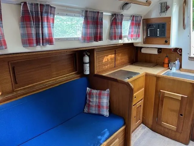 Slide: The Image of 1978 Bristol 29.9 boat interior with blue seating, plaid curtains, and wooden cabinetry. - 4