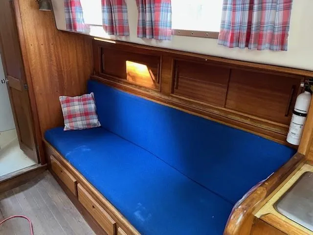 Slide: The Image of 1978 Bristol 29.9 boat interior with blue seating, plaid curtains, and wooden accents. - 5