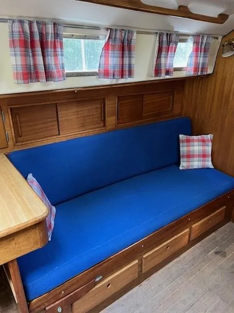 Slide: The Image of Interior of a 1978 Bristol 29.9 sailboat with blue seating and plaid curtains. - 6