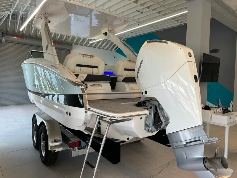 Slide: The Image of 2025 Regal LX6 boat on trailer, featuring a powerful outboard motor in a showroom. - 2
