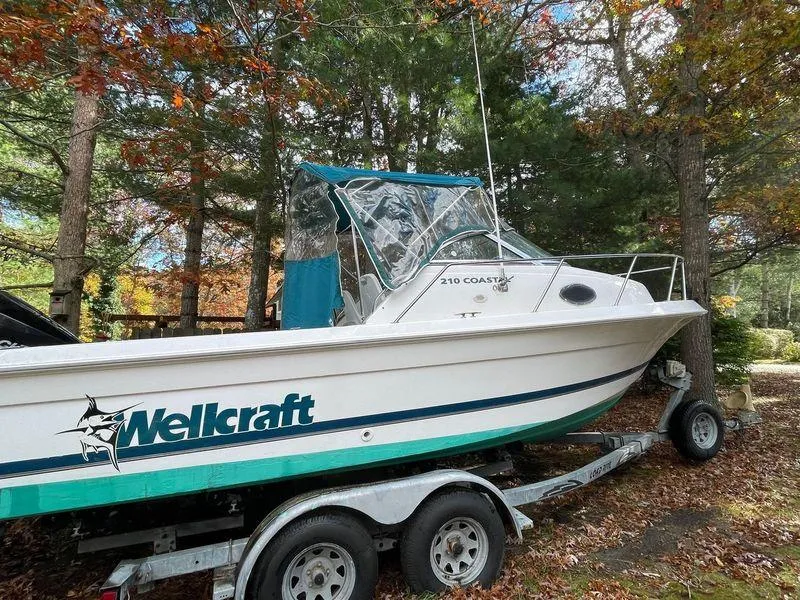 Slide: The Image of 1998 Wellcraft 210 Coastal boat on trailer, surrounded by trees. - 3