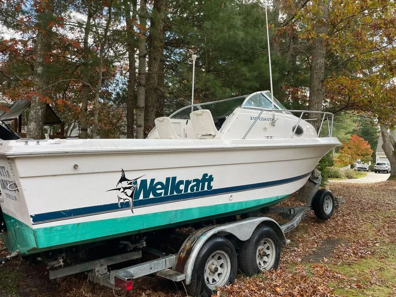 Slide: The Image of 1998 Wellcraft 210 Coastal boat on trailer, surrounded by trees in a yard. - 4