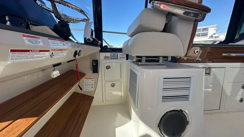 Slide: The Image of Interior of 2025 Boston Whaler 405 Conquest boat, featuring helm seating and control panel. - 38