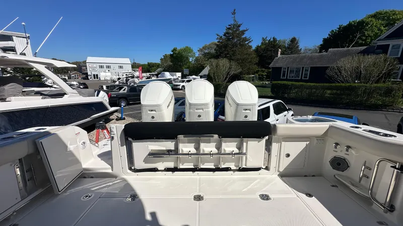 Slide: The Image of 2025 Boston Whaler 405 Conquest boat with triple outboard engines, docked in a marina. - 4