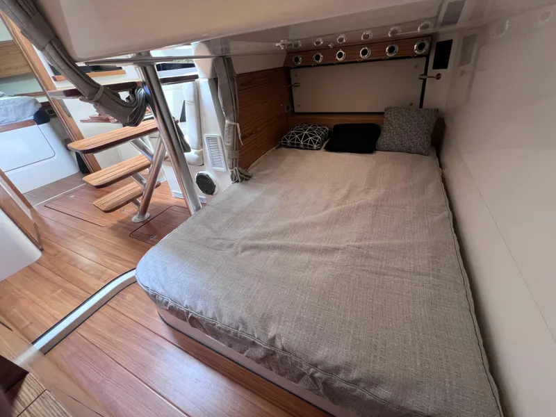 Slide: The Image of 2025 Boston Whaler 405 Conquest cabin interior with cozy bed and wooden flooring. - 43