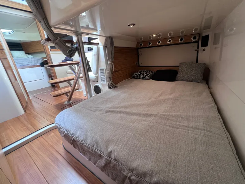 Slide: The Image of 2025 Boston Whaler 405 Conquest cabin interior with cozy bed and wooden flooring. - 44