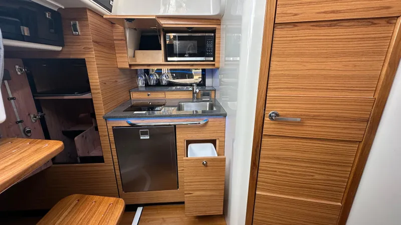 Slide: The Image of 2025 Boston Whaler 405 Conquest interior kitchen with wood finish, sink, and appliances. - 47