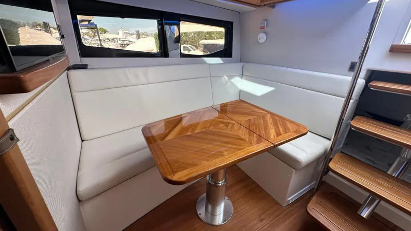 Slide: The Image of Interior of 2025 Boston Whaler 405 Conquest with elegant wood table and white seating. - 48