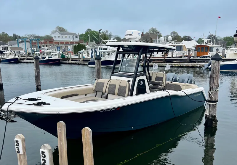 Slide: The Image of 2020 Tidewater 252 LXF boat docked in a marina, surrounded by other vessels. - 2