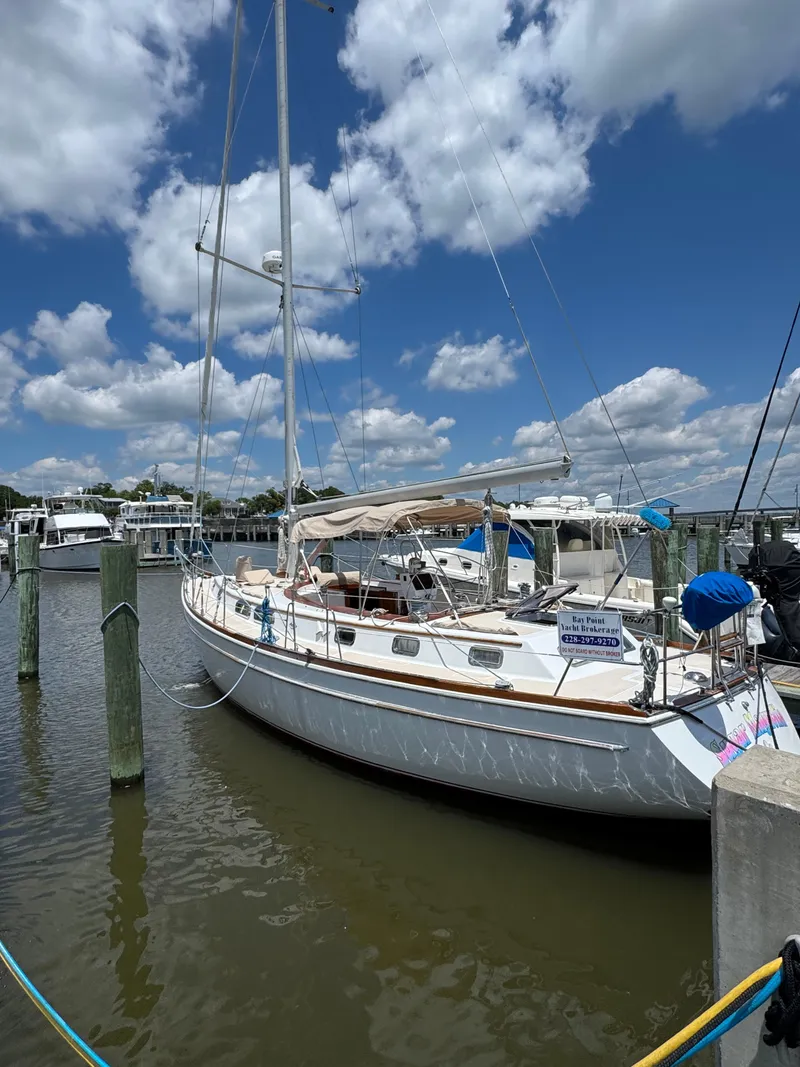 The Image of 1981 Gulfstar 44 sailboat docked under a bright blue sky with scattered clouds. - 0