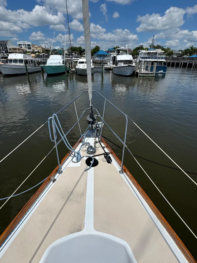 Slide: The Image of Bow view of 1981 Gulfstar 44 sailboat docked in a marina under a partly cloudy sky. - 11