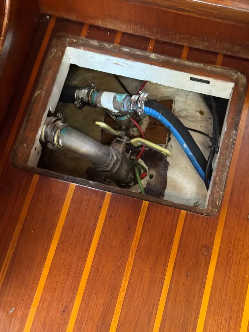Slide: The Image of 1981 Gulfstar 44 yacht interior showing plumbing and wiring beneath wooden floor panel. - 34