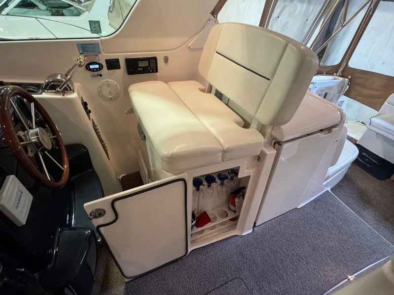 Slide: The Image of 2004 Tiara Yachts 3600 Sovran helm with white seating and storage compartment. - 11