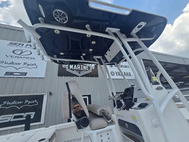 Slide: The Image of 2021 Sea Pro 228 Bay boat with T-top and console, displayed at a marine dealership. - 15