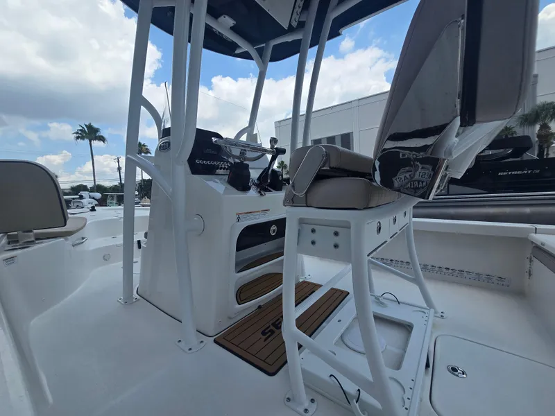 Slide: The Image of 2021 Sea Pro 228 Bay boat interior with seating and console, under a blue sky. - 6