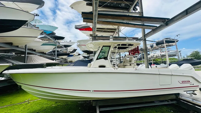 Slide: The Image of 2020 Boston Whaler 330 Outrage boat in storage, surrounded by other vessels. - 17