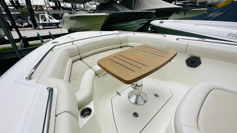 Slide: The Image of 2020 Boston Whaler 330 Outrage boat interior with cushioned seating and wooden table. - 6