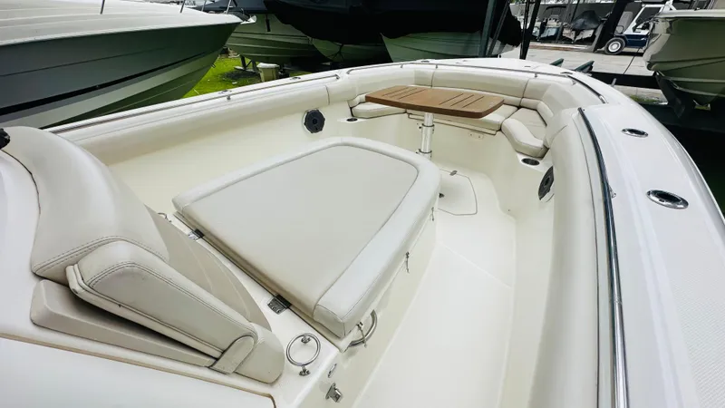 Slide: The Image of 2020 Boston Whaler 330 Outrage boat interior with cushioned seating and wooden table. - 7
