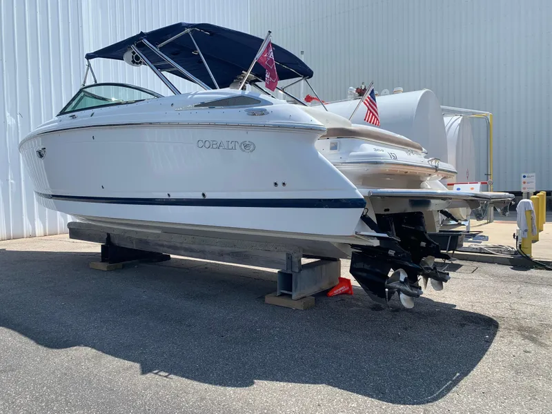Slide: The Image of 2014 Cobalt 302 boat with blue canopy, docked on land. - 2