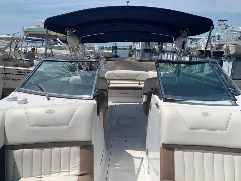 Slide: The Image of 2014 Cobalt 302 boat with white seating and blue canopy at a marina. - 28