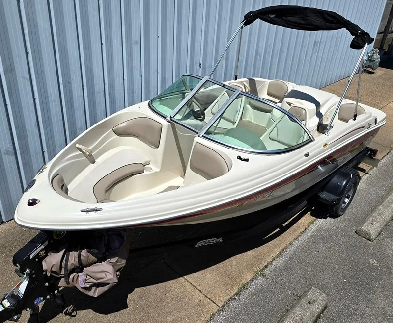 Slide: The Image of 2003 Sea Ray 176 SRX BR boat with canopy, parked on trailer near metal building. - 1