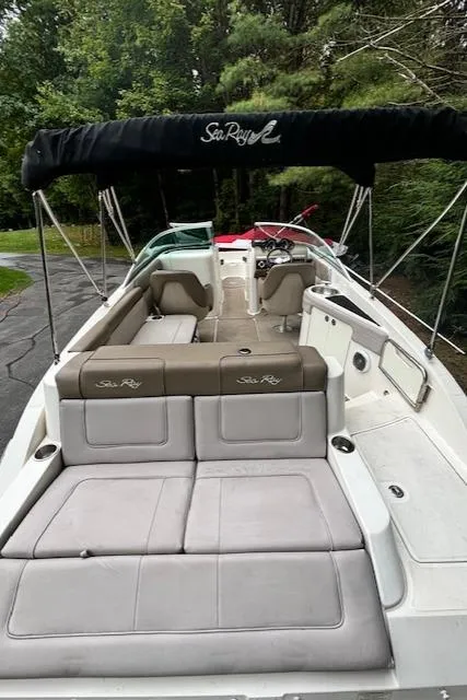 Slide: The Image of 2012 Sea Ray 260 Sundeck boat with spacious seating and canopy, docked near lush greenery. - 15
