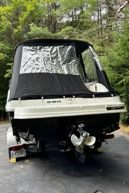 Slide: The Image of 2012 Sea Ray 260 Sundeck boat with black cover, parked on a driveway. - 2