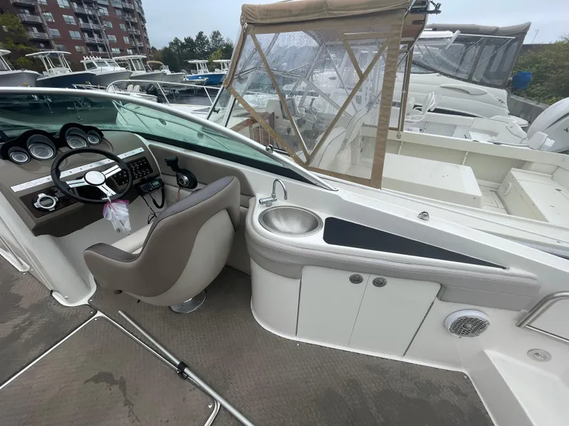 Slide: The Image of 2012 Sea Ray 260 Sundeck interior with helm, sink, and seating at marina. - 7