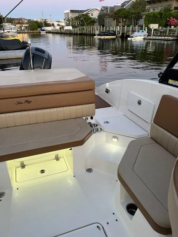 Slide: The Image of 2018 Sea Ray SPX 230 Outboard boat interior with beige seating, docked by a canal. - 11