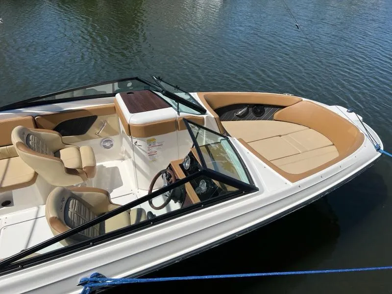 Slide: The Image of 2018 Sea Ray SPX 230 Outboard boat with tan seating, docked on calm water. - 2