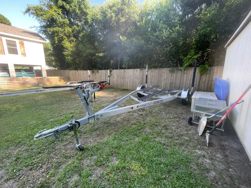 Slide: The Image of Empty boat trailer in a grassy yard, surrounded by trees and a wooden fence. - 19