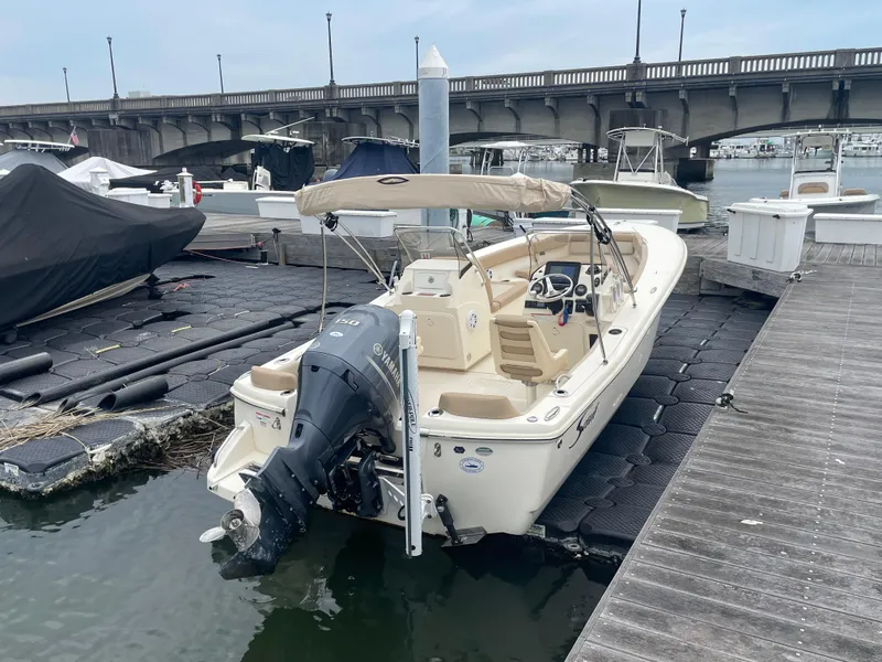 Slide: The Image of 2022 Scout Sport 195 Dorado boat docked near a bridge, featuring an outboard motor. - 3