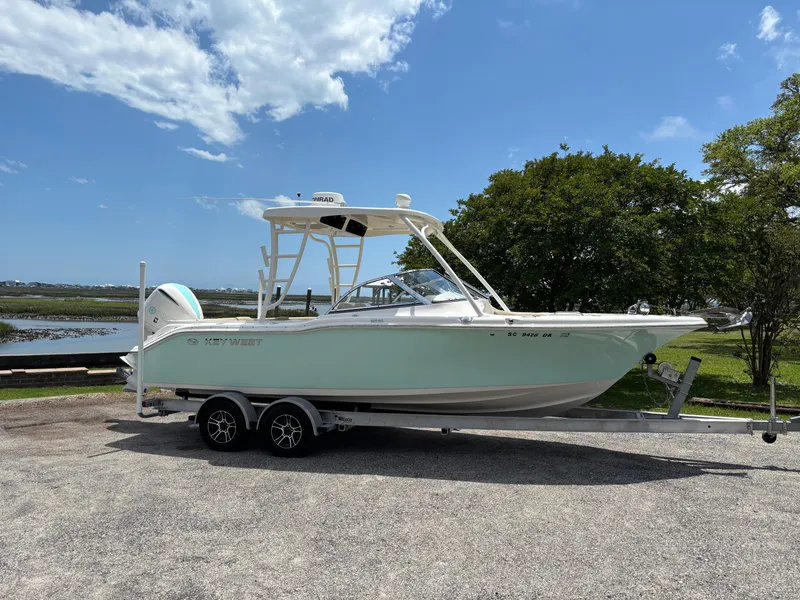 Slide: The Image of 2019 Key West 239 DFS boat on trailer, parked near water under blue sky. - 12