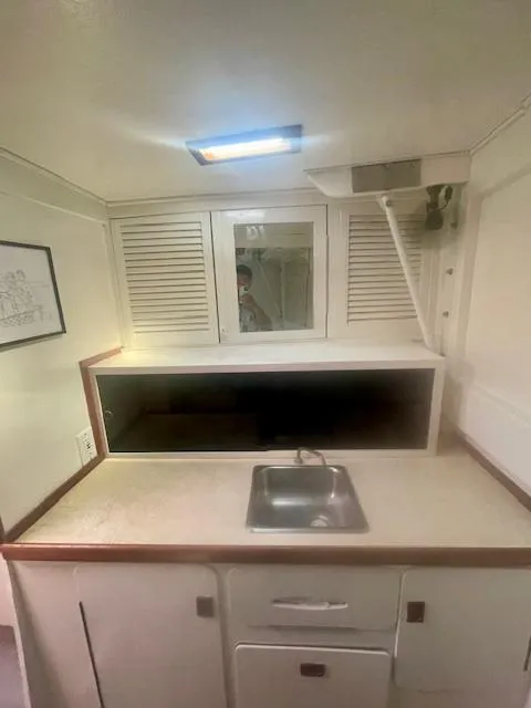 Slide: The Image of 1980 Custom Horstman Tristar Ketch interior with compact kitchen sink and storage cabinets. - 16