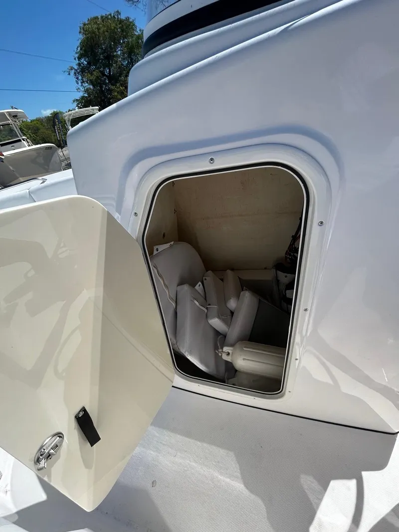 Slide: The Image of 2022 Aquasport 2100 boat storage compartment with open hatch, showing interior space. - 7