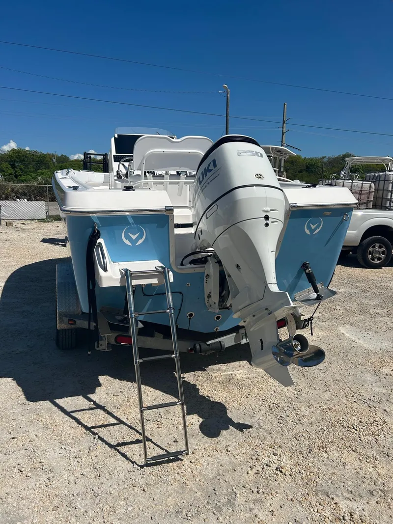 Slide: The Image of 2022 Aquasport 2100 boat with outboard motor and ladder, parked on gravel. - 8