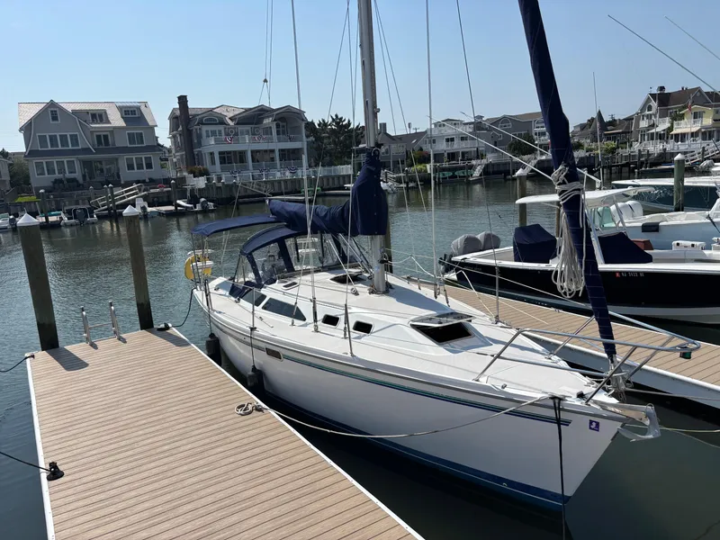 The Image of 1998 Catalina 320 sailboat docked in a marina with waterfront homes in the background. - 0