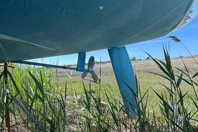 Slide: The Image of Underneath view of a 1998 Catalina 320 sailboat with visible propeller and rudder in grassy area. - 10