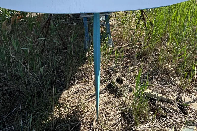 Slide: The Image of Keel of a 1998 Catalina 320 sailboat resting on grass. - 11