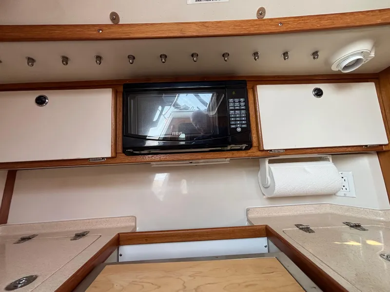 Slide: The Image of 1998 Catalina 320 interior kitchen with microwave, cabinets, and paper towel holder. - 16