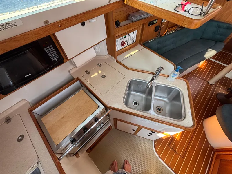 Slide: The Image of Compact kitchen area in a 1998 Catalina 320 sailboat with sink, stove, and microwave. - 17