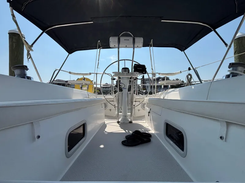 Slide: The Image of 1998 Catalina 320 sailboat cockpit with canopy, steering wheel, and docked marina view. - 20