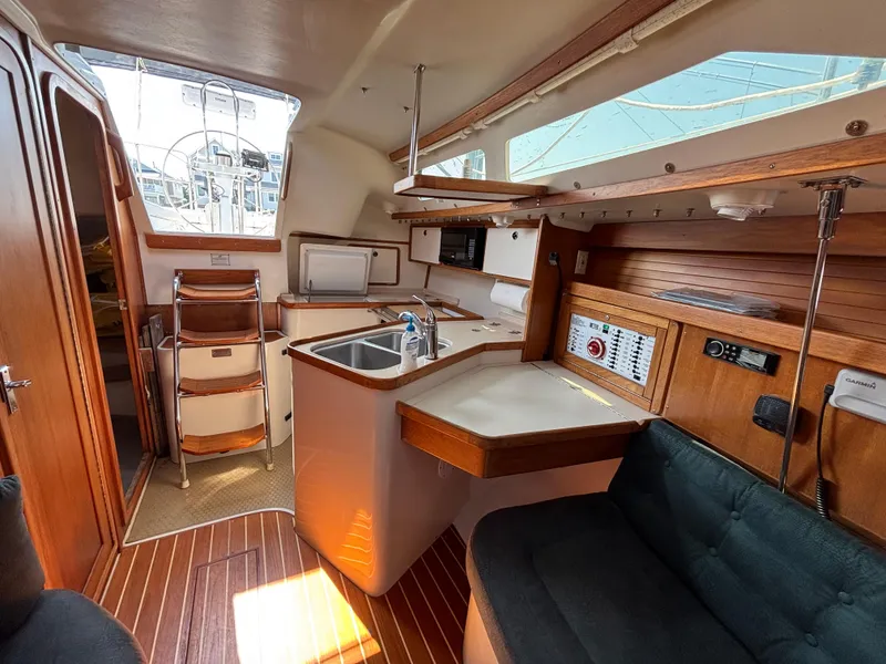 Slide: The Image of Interior of 1998 Catalina 320 sailboat with wooden cabinetry and compact kitchen area. - 24