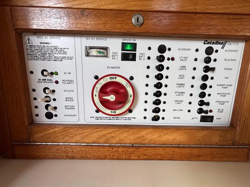 Slide: The Image of Electrical control panel of a 1998 Catalina 320 yacht with various switches and indicators. - 34