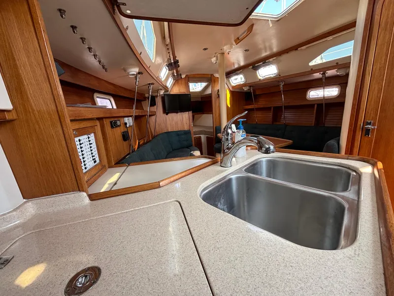 Slide: The Image of Interior of a 1998 Catalina 320 sailboat, featuring a kitchen sink and cozy seating area. - 38