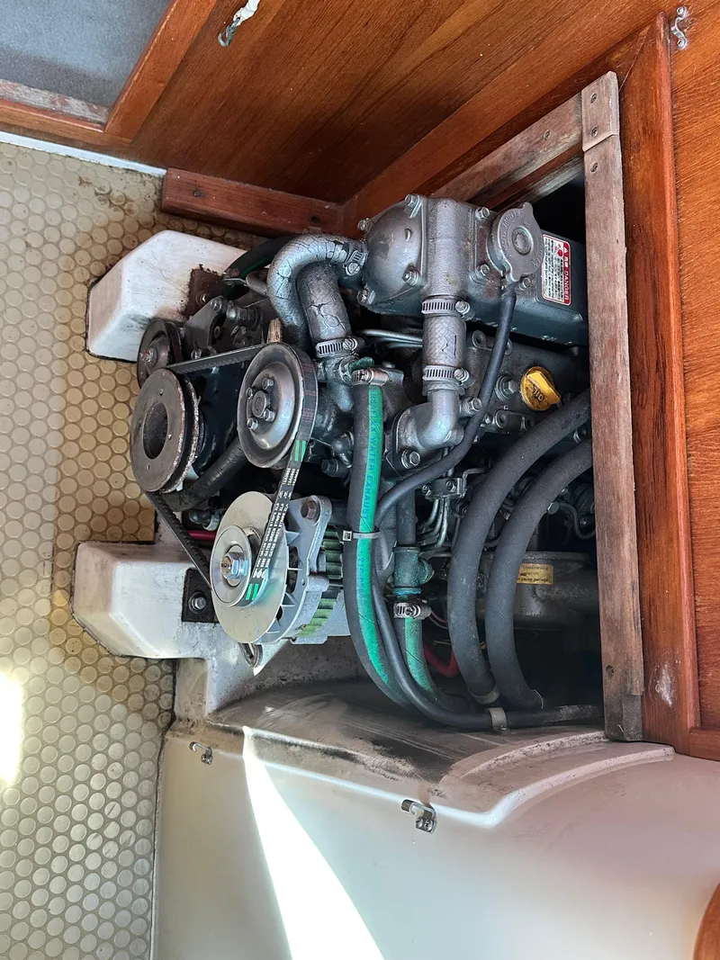 Slide: The Image of Engine compartment of a 1998 Catalina 320 sailboat, showcasing mechanical components and hoses. - 49