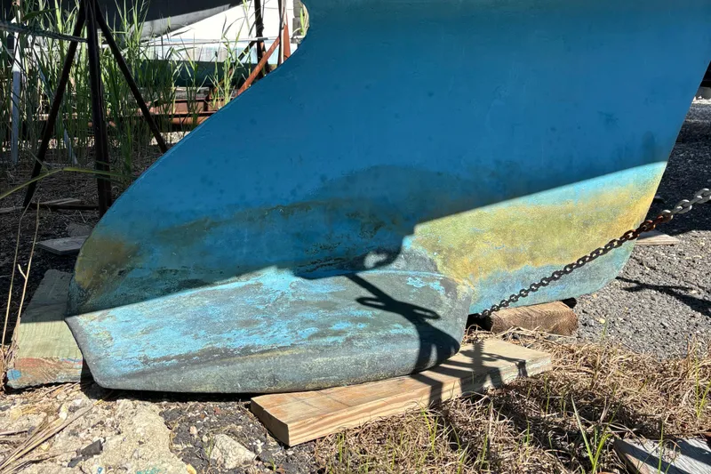 Slide: The Image of Keel of a 1998 Catalina 320 sailboat on dry land, showing weathered blue paint. - 5